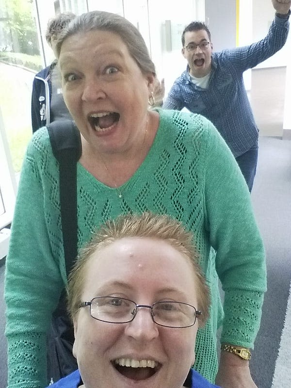 A photo of Ruth, seated in a wheelchair, and three friends behind her having fun, smiling and laughing.