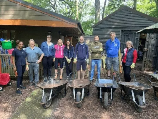 The Acquia team who spent the day at Camp Mohawk standing behind four wheelbarrows.